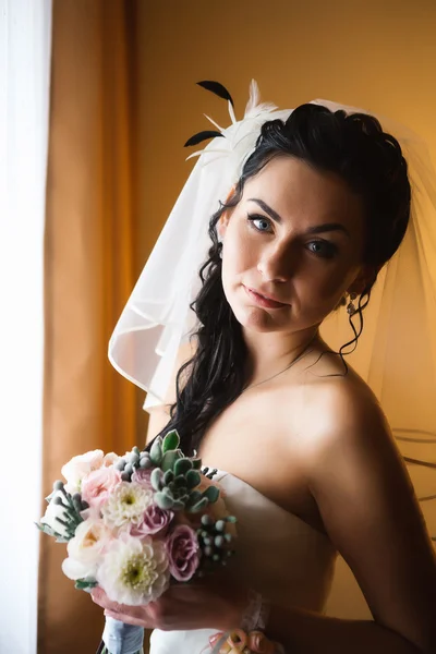 Schöne junge glückliche Braut steht am Fenster — Stockfoto