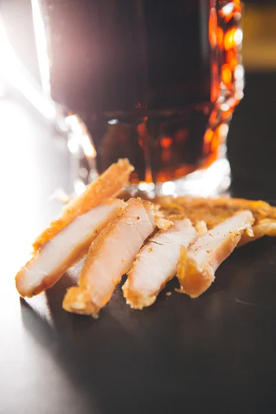 Стакан свежего пива и сушеная курица на деревянном столе — стоковое фото