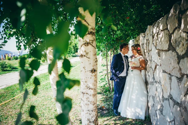 Счастливая пара невесты и жениха обнимая они стоят на фоне каменной стены крупным планом — стоковое фото