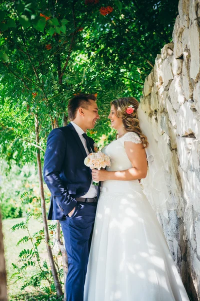 Heureux couple mariée et marié embrassant ils se tiennent sur fond mur de pierre gros plan — Photo