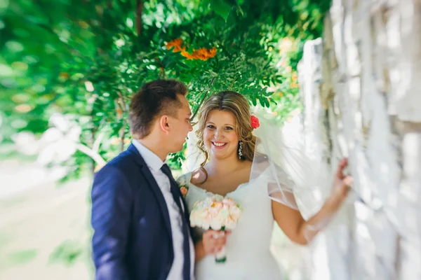 Happy couple bride and groom embracing they stand on background stone wall close-up — Stock Photo, Image