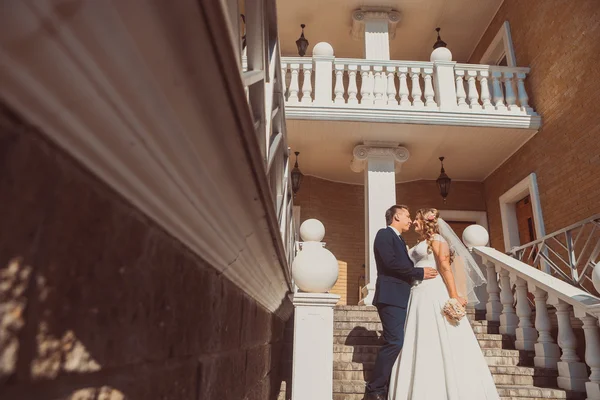 Обнимая невесту и жениха, они стоят на заднем плане красивой архитектуры города на всю длину — стоковое фото