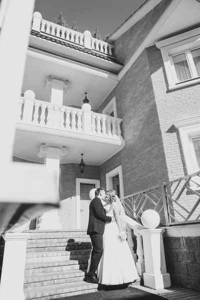 Bruid en bruidegom omarmen ze staan op de achtergrond mooie architectuur van de stad volledige lengte — Stockfoto