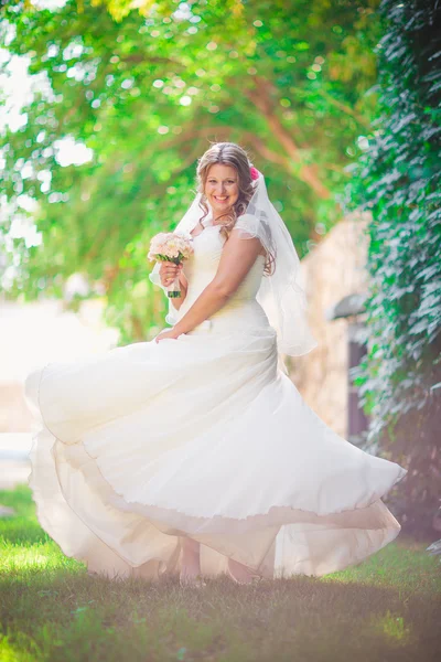 Elegante bella sposa felice tenendo bouquet di fiori su uno sfondo alberi nel parco estivo a tutta lunghezza — Foto Stock