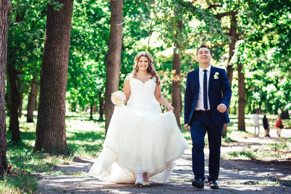 Casal feliz noiva e noivo caminhar abraçando em uma floresta de comprimento total — Fotografia de Stock