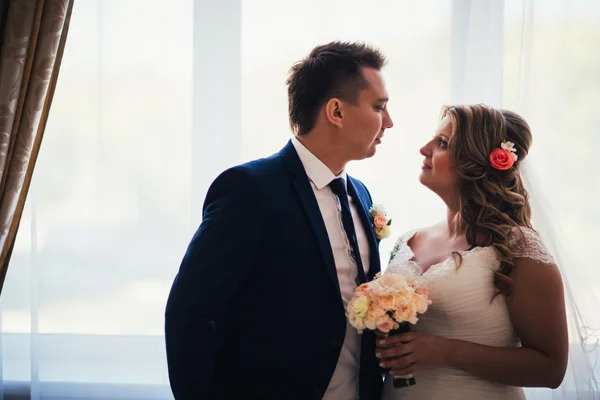 Bride and groom posing in a hotel room on background windows — Stock Photo, Image