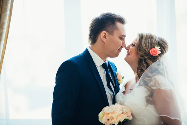 Bruid en bruidegom poseren in een hotelkamer op achtergrond windows — Stockfoto