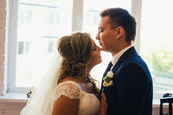 Bruid en bruidegom poseren in een hotelkamer op achtergrond windows — Stockfoto