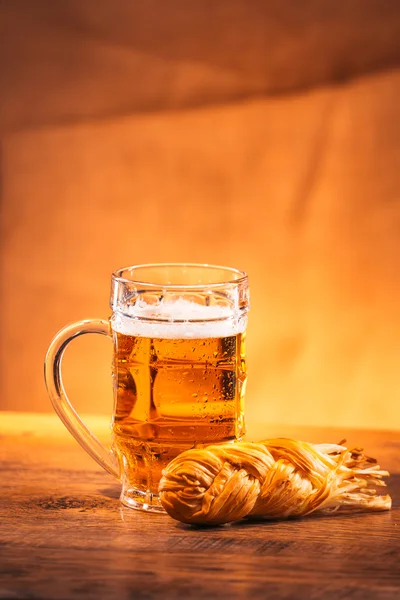 Стакан свежего яркого пива с копченой сырной косой на упаковке — стоковое фото