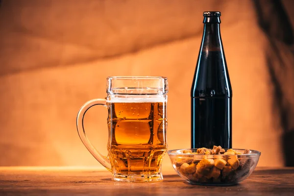 Стакан свежего яркого пива и крекеров на деревянном столе — стоковое фото