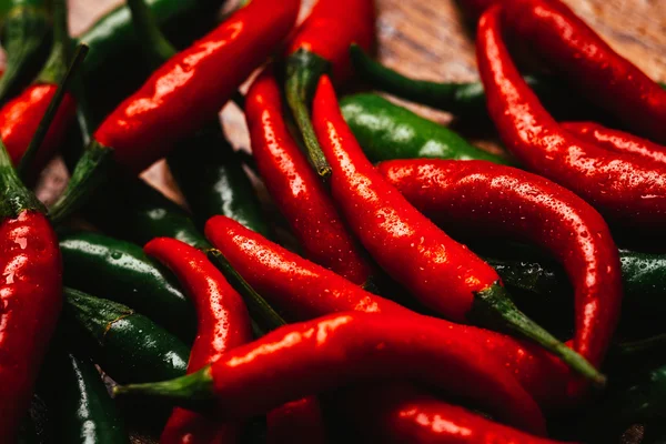 Red and green chili peppers close up on wooden background — Stock Photo, Image