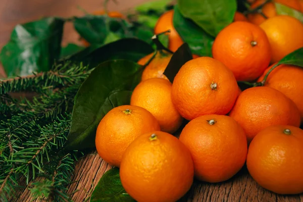 Viele frische Mandarinen und Tannenzweige auf einem hölzernen Hintergrund — Stockfoto