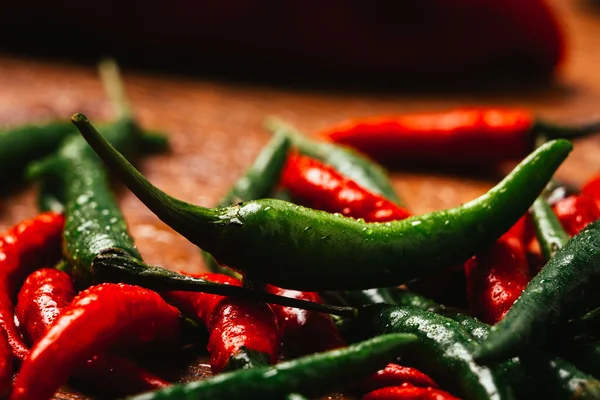 Red and green chili peppers close up on wooden background — Stock Photo, Image