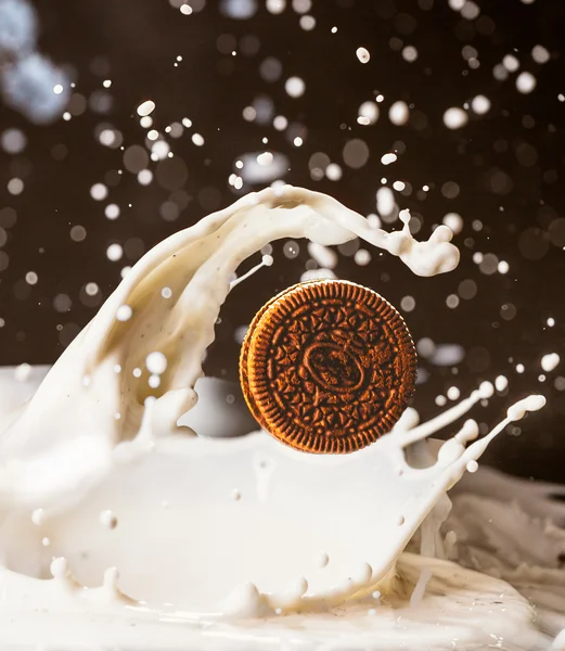 Kekse und Milchspritzer auf dunklem Hintergrund — Stockfoto