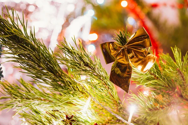 Golden bow on a background of green Christmas tree branches — Stock Photo, Image