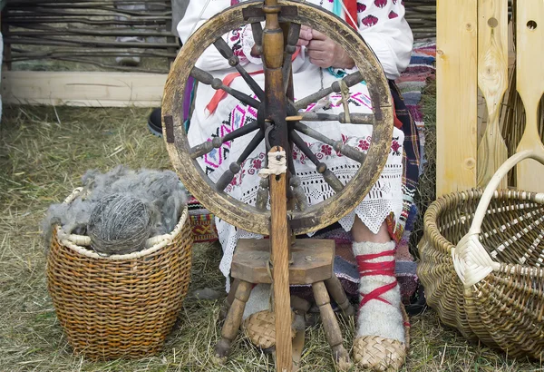 Una donna anziana filatura filo su una ruota di filatura . — Foto Stock