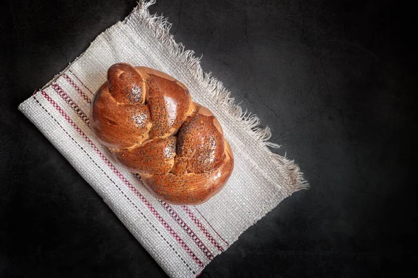 亚麻布餐巾上有一块白色的面包 形状是用罂粟籽和脆皮做成的斑块 呈现在黑暗的背景上 顶部视图 复制空间 — 图库照片