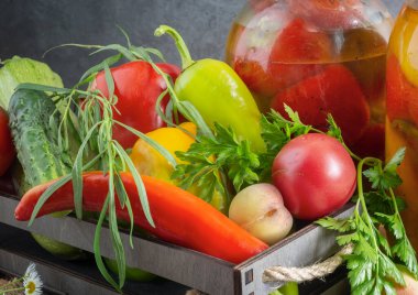 Cam kavanozlarda, konserve dolmalık biberlerde bir kutu biber ve diğer sebzelerin yanında. Ön manzara, yakın plan.