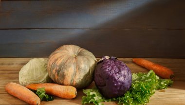 Hayat devam ediyor: bodrumdaki ahşap bir rafta kabaklar, havuçlar, kırmızı lahana ve beyaz lahana var. Ön görünüm, boşluğu kopyala
