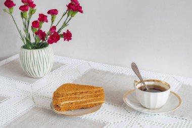 Alternatif kahve yerine, beyaz bir fincanda masanın üzerinde doğal hindibasından yapılmış sıcak kafeinsiz bir içecek. Lezzetli bir pasta ve çiçeğin yanında. Kopyalama alanı ile ön görünüm.