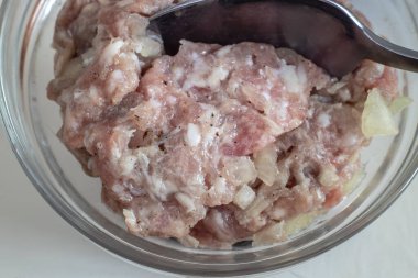 Masanın üzerinde cam bir kasede, soğanlı ve baharatlı et kıymalı hamur tatlısı ve pirzola yapmak için. Yakın çekimde sunuldu. Ev yapımı yemek..