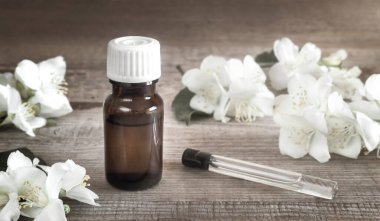 Yasemin yağı ve beyaz yasemin çiçekleri masada.