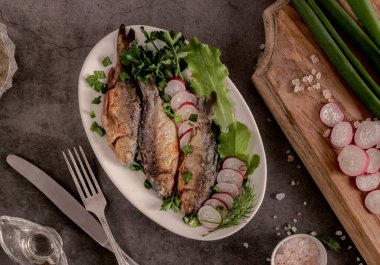 Tabakta kızarmış sazan, turp, yeşil soğan ve marul var. Üst görünüm, yakın çekim.