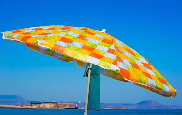 Sunshades and clothes on a sea beach — Stock Photo, Image