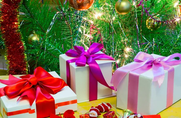 Schön verpacktes Weihnachtsgeschenk und geschmückter Tannenbaum. — Stockfoto