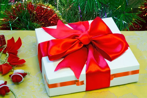 Beautifully packed gift by Christmas and the decorated fir-tree. — Stock Photo, Image