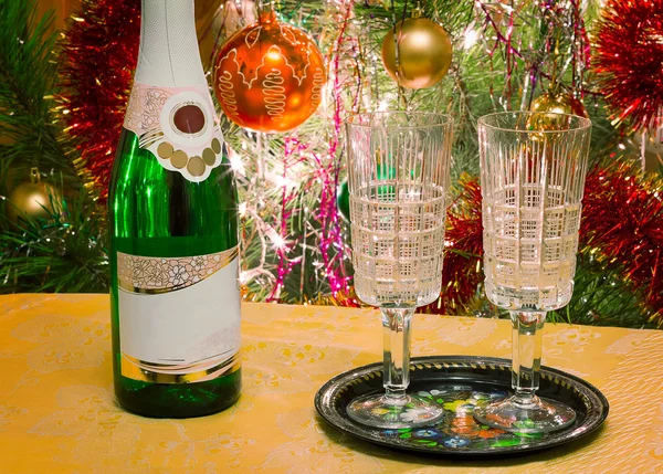 Christmas holiday, wine and glasses near a Christmas fir-tree. — Stock Photo, Image