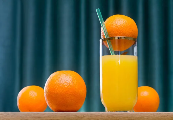 Jus d'orange dans un verre et des oranges sur la table . — Photo