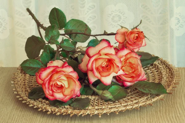Le rose sul tavolo su un piatto di vimini . — Foto Stock