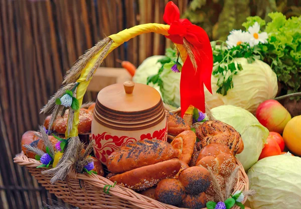 Basket of bread, decorated with ribbons, and vegetables — Stock Photo, Image