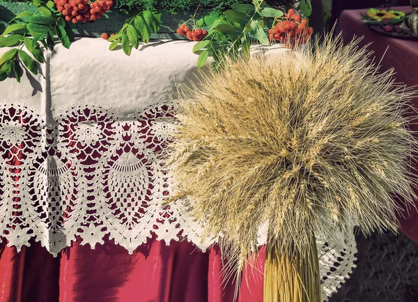 A sheaf of wheat on a background of lace fabric. — Stock Photo, Image