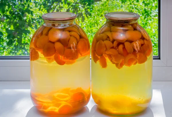 Home canning: large glass cylinders with apricot compote. — Stock Photo, Image