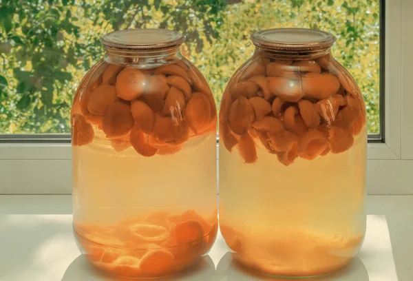 Home canning: large glass cylinders with apricot compote. — Stock Photo, Image