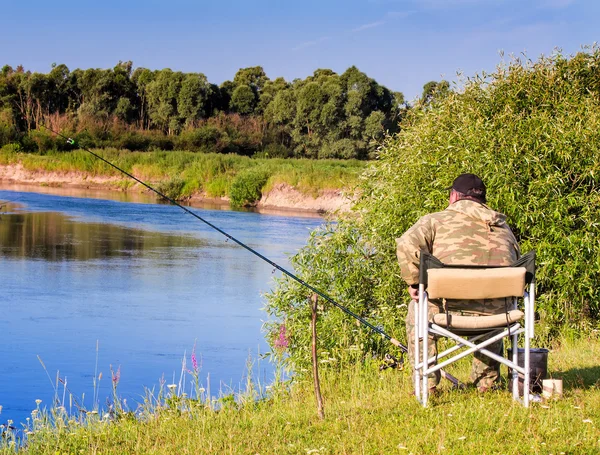 Pescatore con una canna da pesca sulla riva del fiume. — Foto Stock