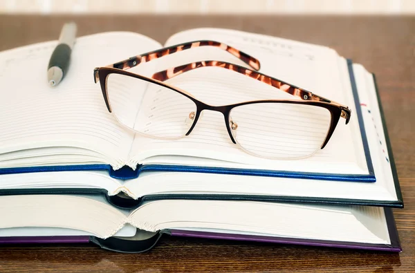 Glasses, books and notebook on the table surface. — Stock Photo, Image