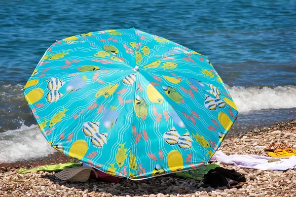 Sunshades and clothes on a sea beach — Stock Photo, Image