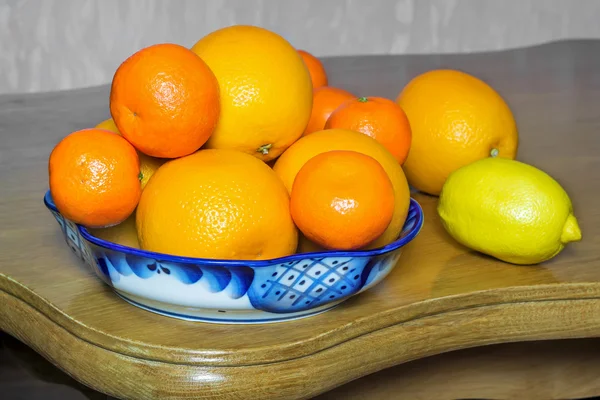 Naranjas y mandarinas en un hermoso jarrón de cerámica . Imagen de stock