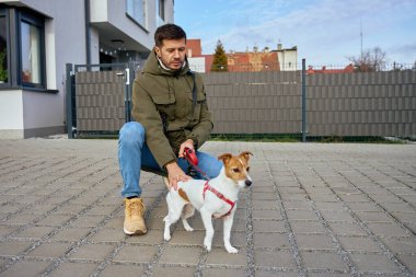 Apartman binalarının yanındaki kaldırımda küçük bir köpeği gezdirirken çömelmiş ve tasma tutuyordu. Hayvan sahibi olma kavramı