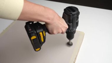 Çalışma yüzeyinde kaplamalı tahtada delik açmak için kablosuz matkap kullanan kişiyi kapatın. DIY kavramı, ahşap işçiliği