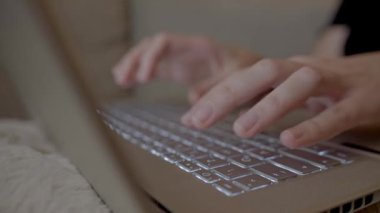 Eller evdeki koltukta otururken dizüstü bilgisayarda klavyede yazıyor. Uzaktan çalışma ve çevrimiçi iletişim kavramı
