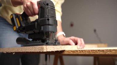 Elektrikli yapboz, insan içeride çalışırken parçacık tahtasını kesiyor. DIY ev geliştirme kavramı