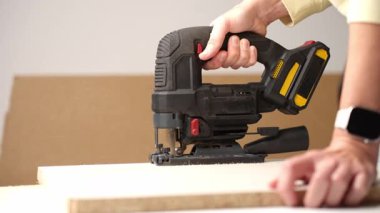 İçerideki ahşap paneli keserken elektrikli yapboz kullanan kişiye yakın çekim. DIY ahşap işçiliği kavramı