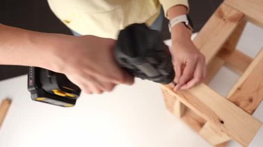 Tahta mobilyalara vida takmak için kablosuz matkap kullanan birinin üst görüntüsü. DIY mobilya montajı kavramı