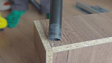 Vakum hortumunun kapatılması, delinen deliğin yanındaki ahşap mobilya panelinden talaş kaldırıyor. Mobilya montaj temizliği kavramı