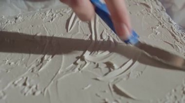 Kadının palet bıçağı ve kalın tutkal kullanarak tuvalde dokulu bir rahatlama yaratmasına yakın çekim. Soyut sanat süreci kavramı