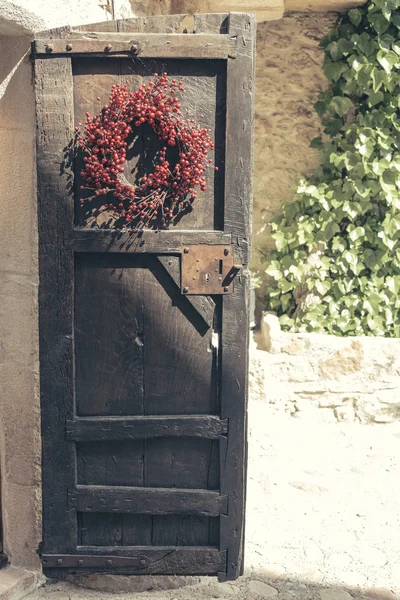 Vecchia porta marrone in legno con decorazione corona rossa — Foto Stock